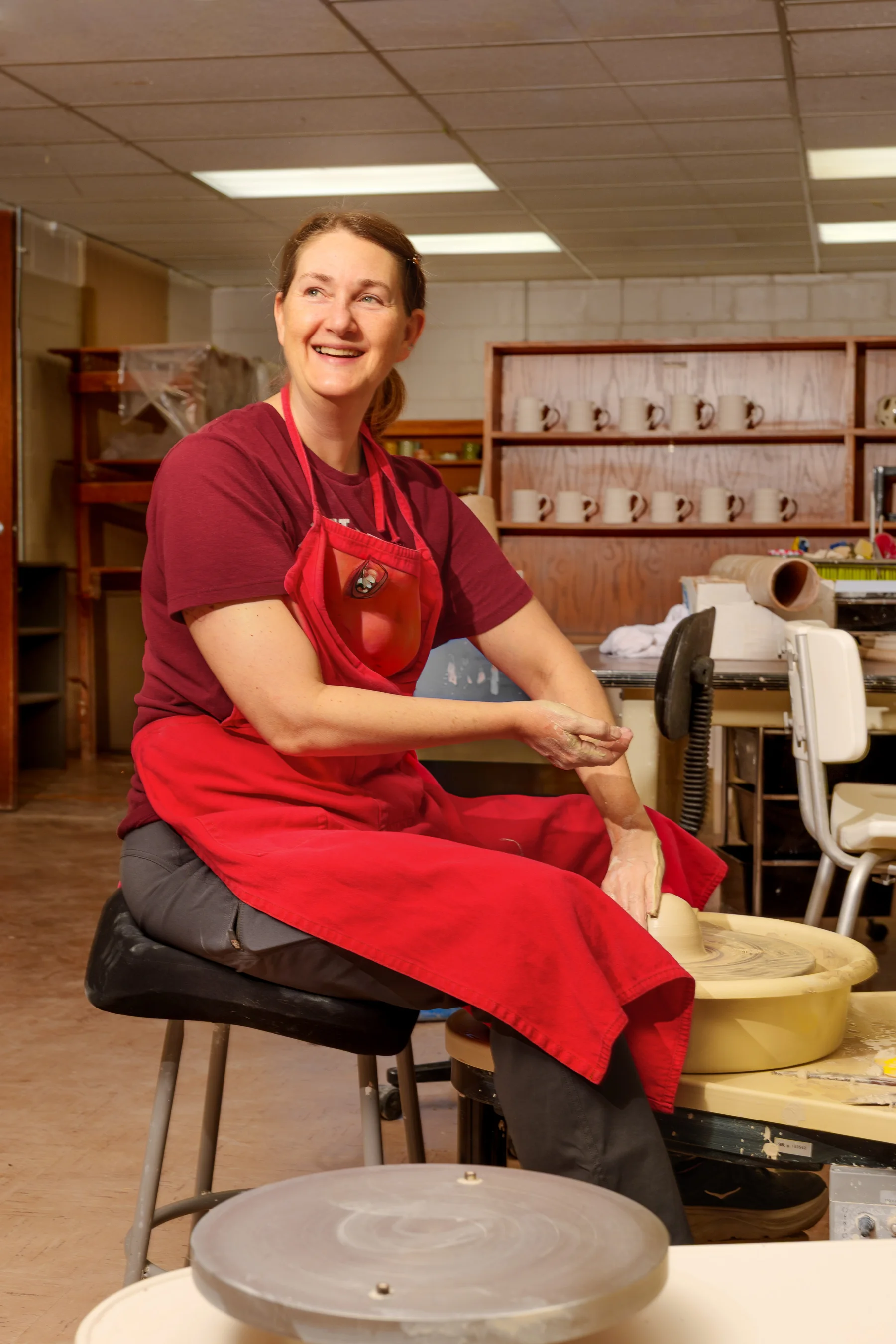 CASA artist Jennifer Quimby smiling while working at a pottery wheel