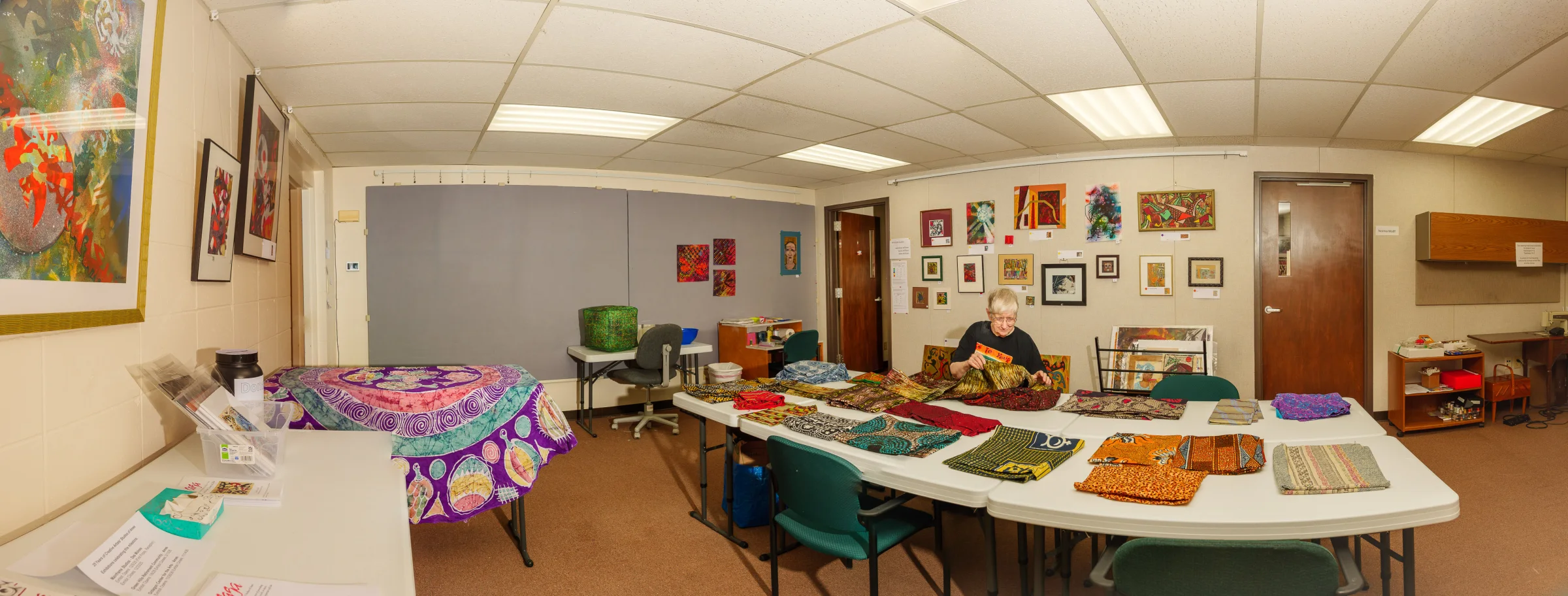Wide view of an actual CASA studio room with shared work tables and artwork